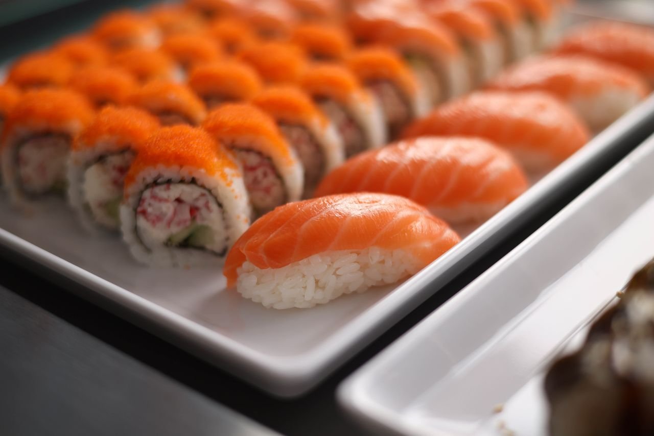 A close-up of vibrant salmon nigiri and sushi rolls on a white platter, perfect for food enthusiasts.